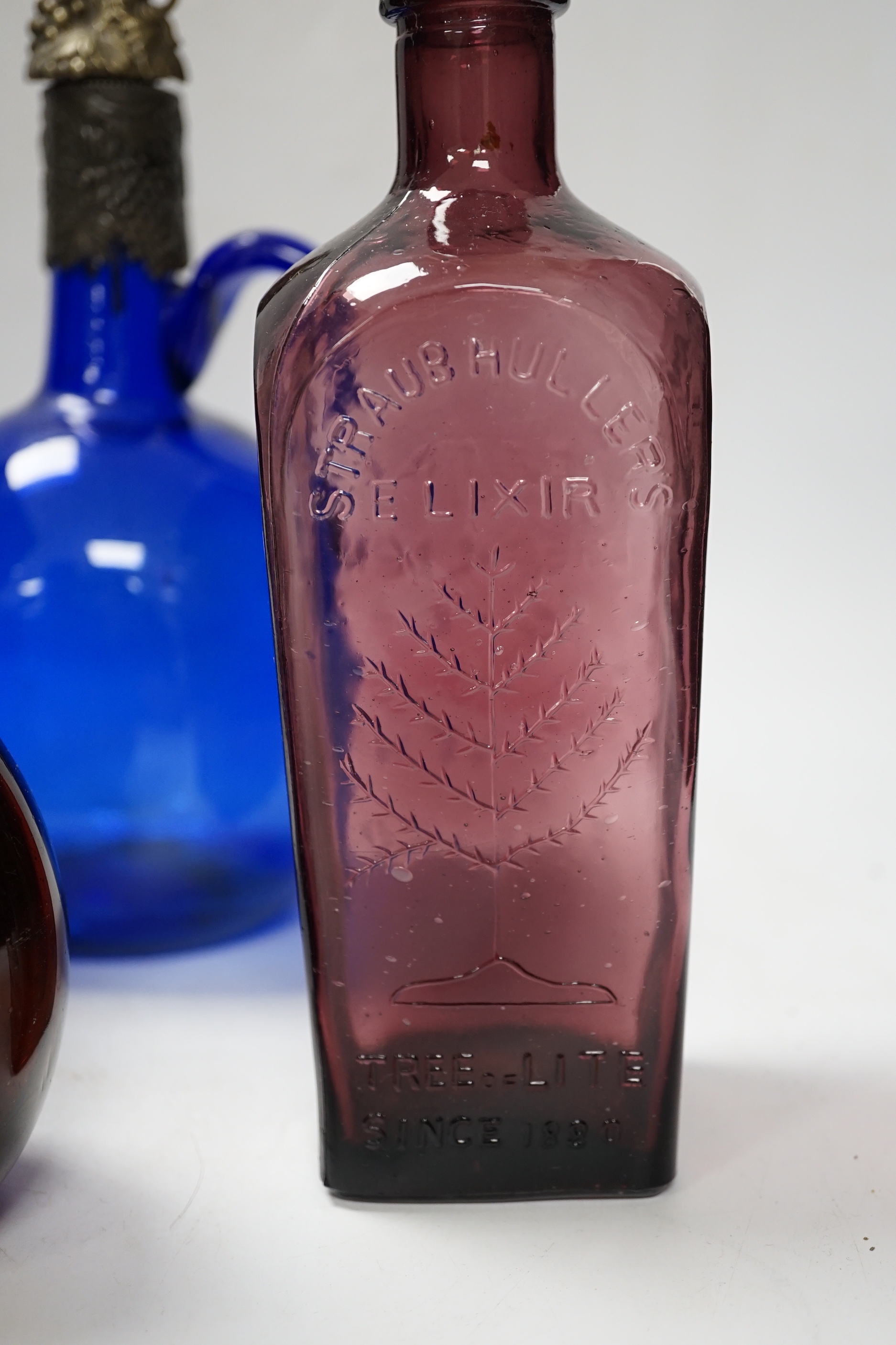 Twelve coloured glass bottles including one in the form of a violin, largest 37cm high